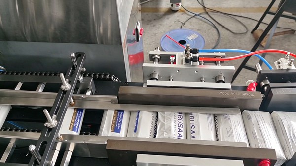 Sealing and conveying section of double layer soap cellophane wrapping machine, finished soap packs on chain conveyor