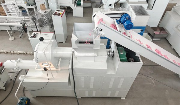 Top view of soap refiner and vacuum plodder machine, inclined conveyor transporting pink soap noodles