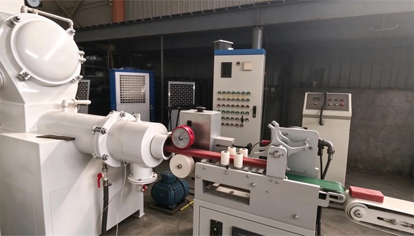 Soap plodder machine extruding red soap bar with cutting device